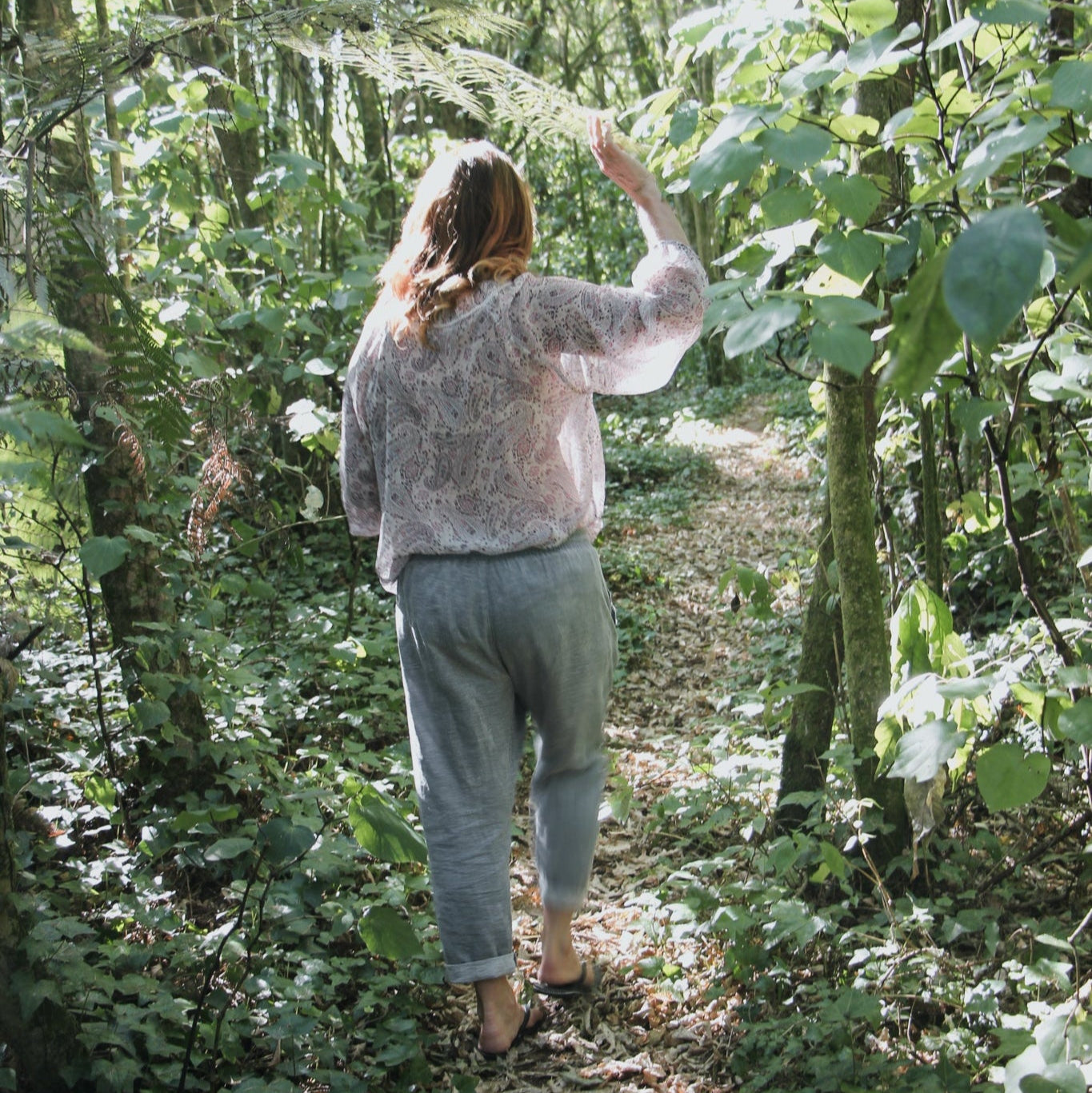 Lady walking through forest of kawakawa