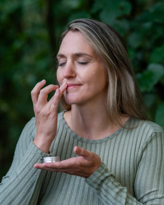 Female applying Koa Botanics Kawakawa Lip Balm.