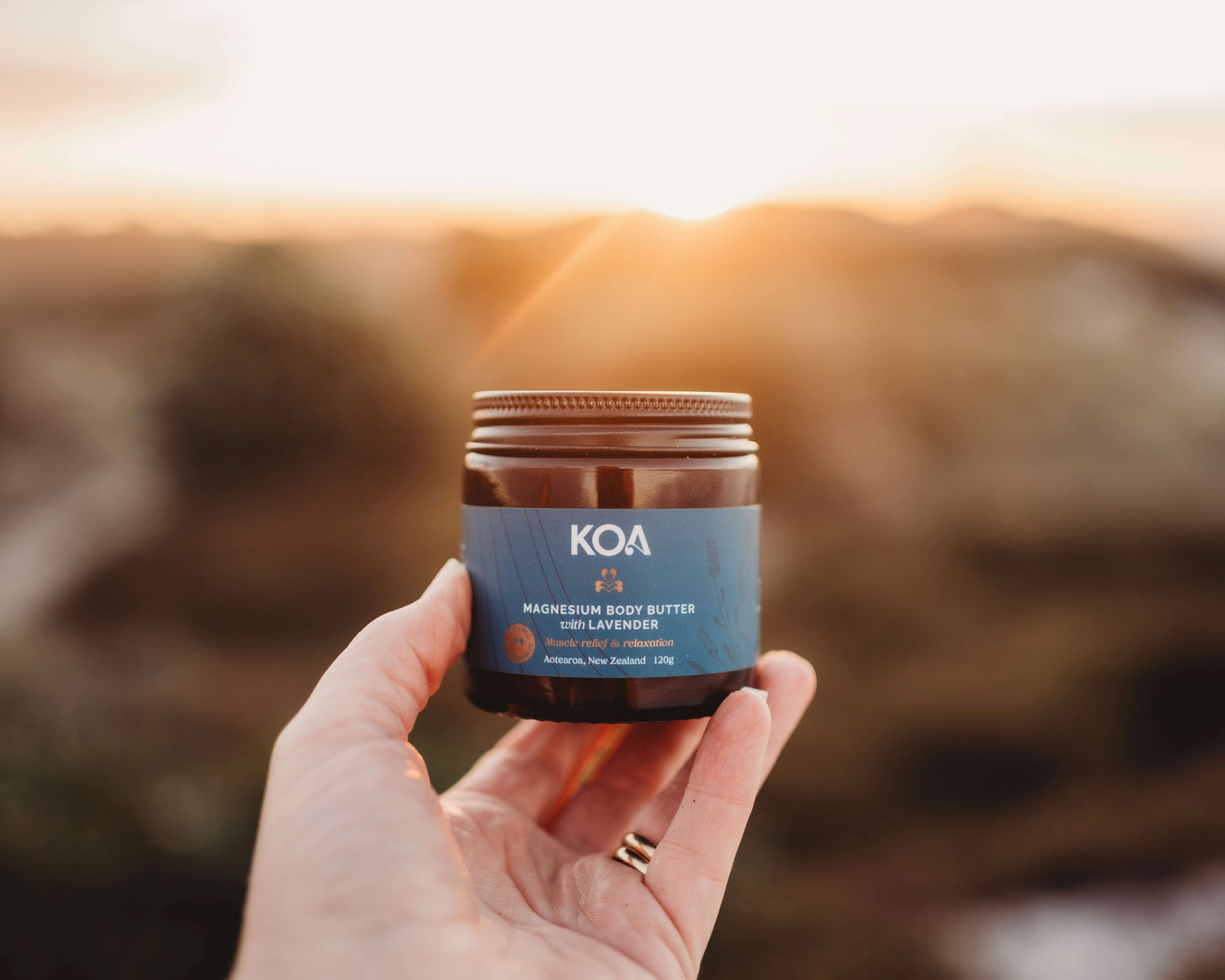 Magnesium Butter with Lavender being held in a hand with a scenic background.