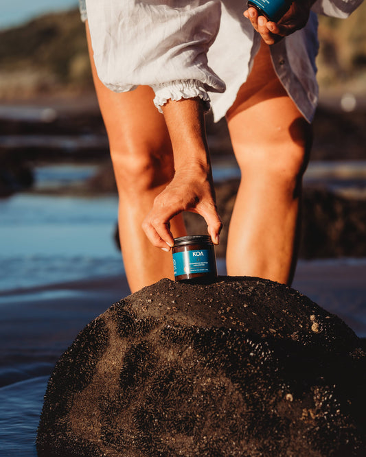 Magnesium Butter Unscented sitting on a rock with a female behind reaching down to pick it up.