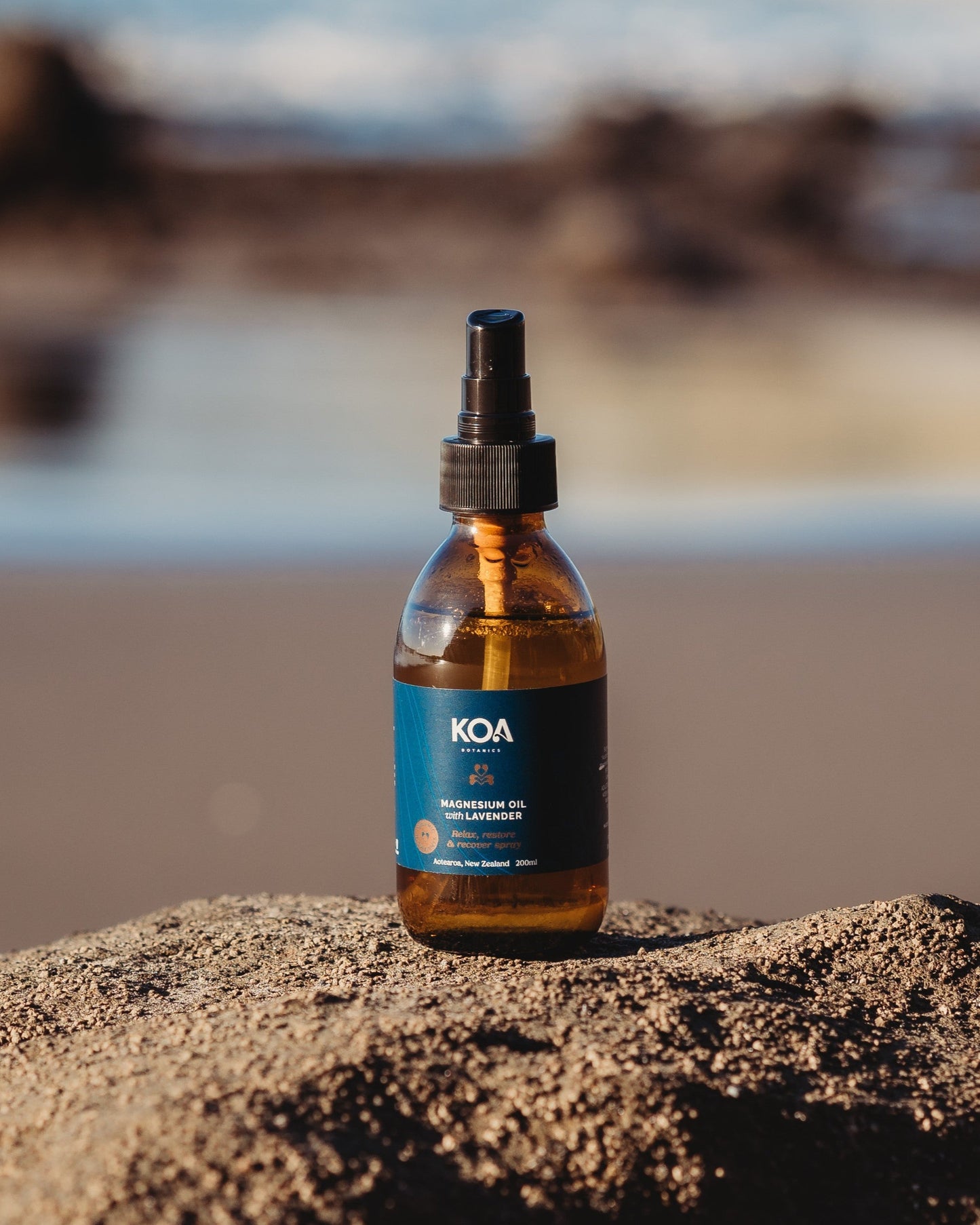 Magnesium Oil with Lavender sitting on a rock with an ocean background.