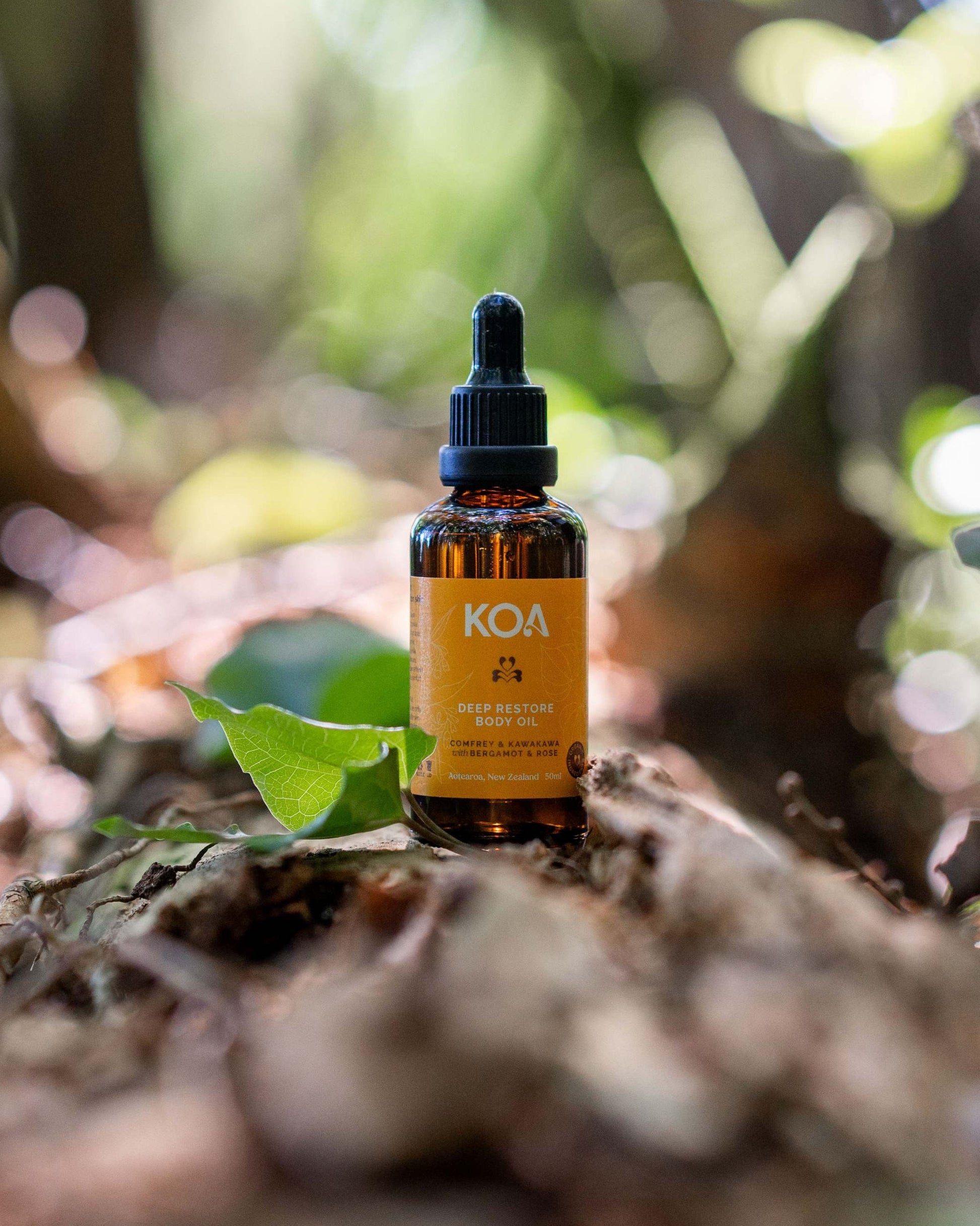 Bottle of KOA Restore oil on a leaf with a blurred natural background