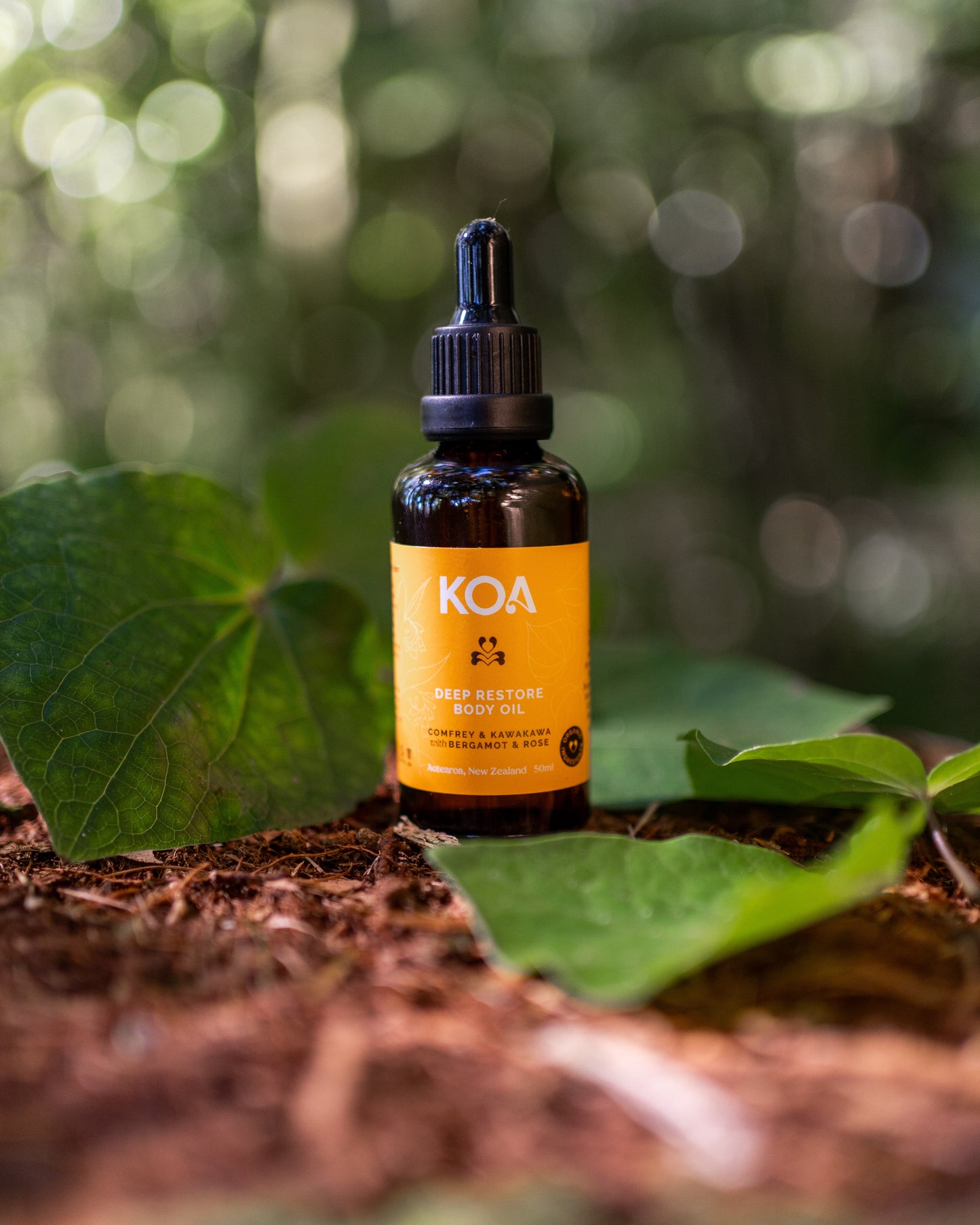 Bottle of KOA oil on a natural background with leaves