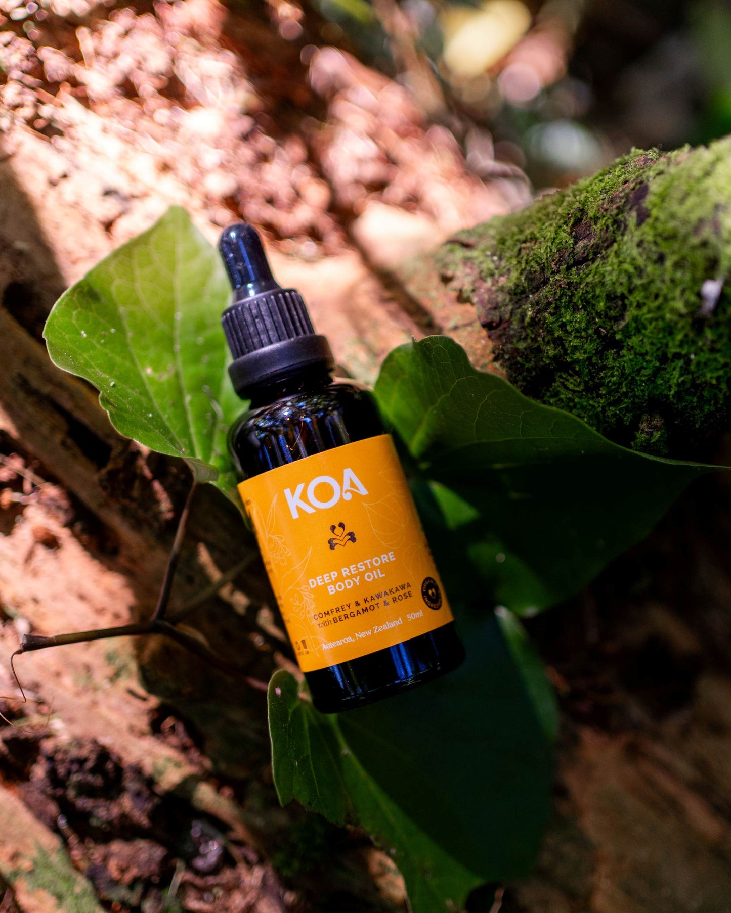 Bottle of Koa Restore oil on a leaf with a natural background