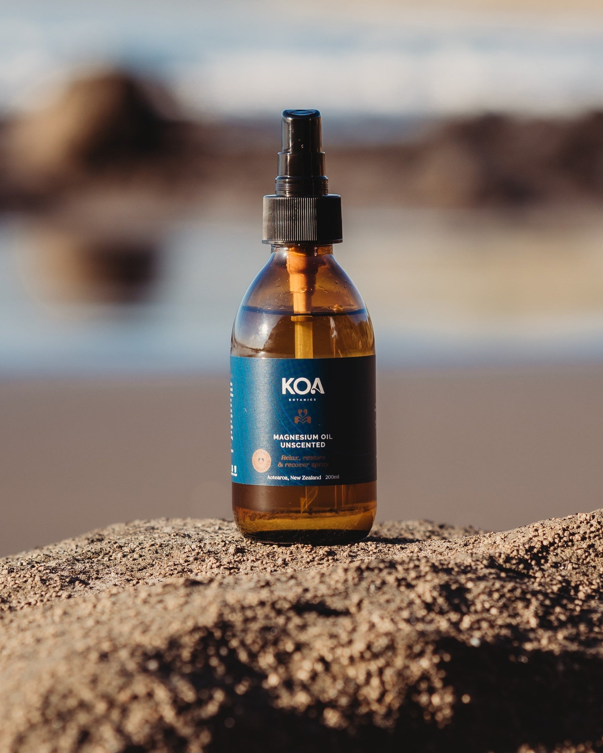 Magnesium Oil Unscented sitting on a rock with an ocean background.
