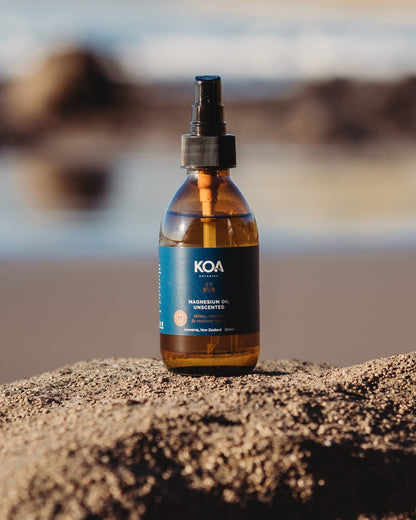 Magnesium Oil Unscented sitting on a rock with an ocean background.