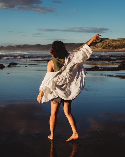 Woman walking along the shoreline with an ocean background. Taken from behind.