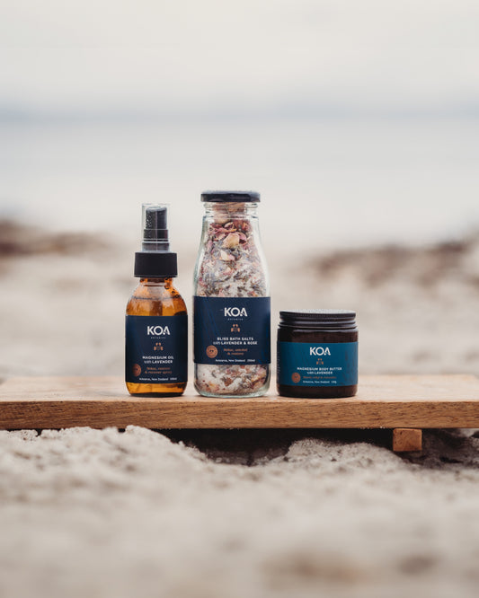 KOA skincare products on a wooden board with a beach background