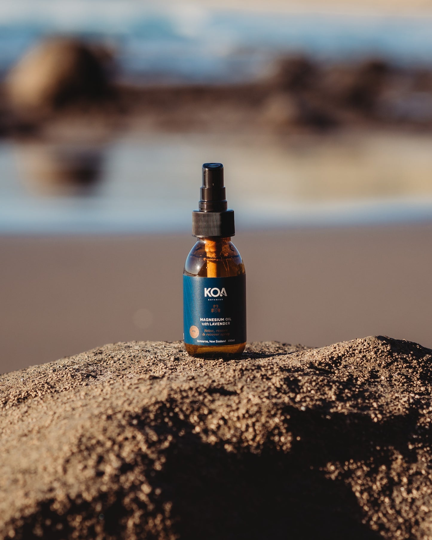Magnesium Oil with Lavender sitting on a rock with an ocean background.