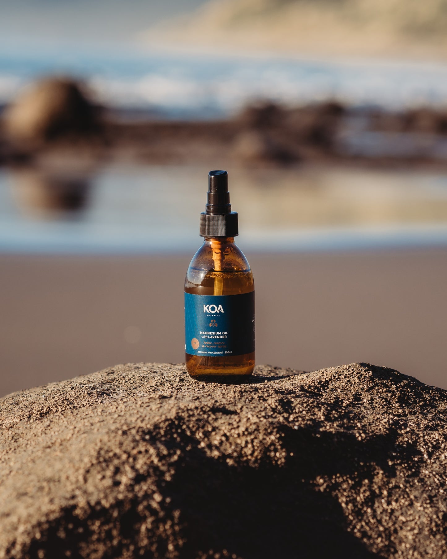 Magnesium Oil with Lavender sitting on a rock with an ocean background.
