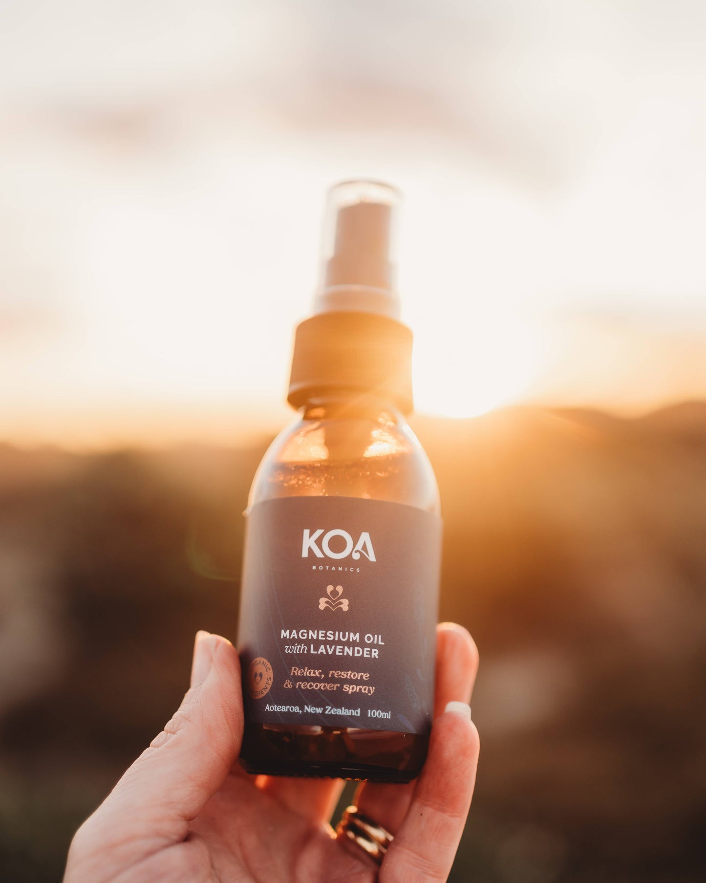 Magnesium Oil with Lavender being held in a hand with a scenic background.