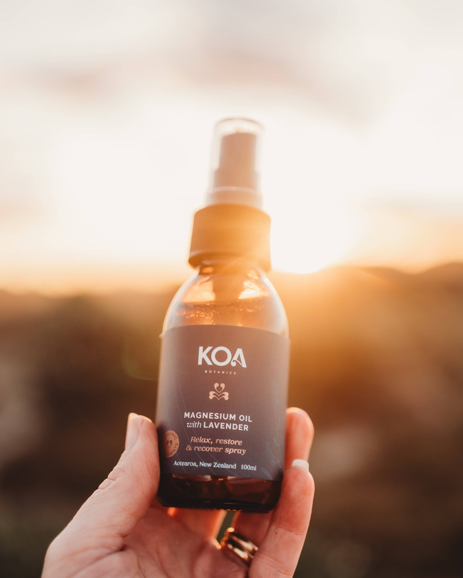 Magnesium Oil with Lavender being held in a hand with a scenic background.