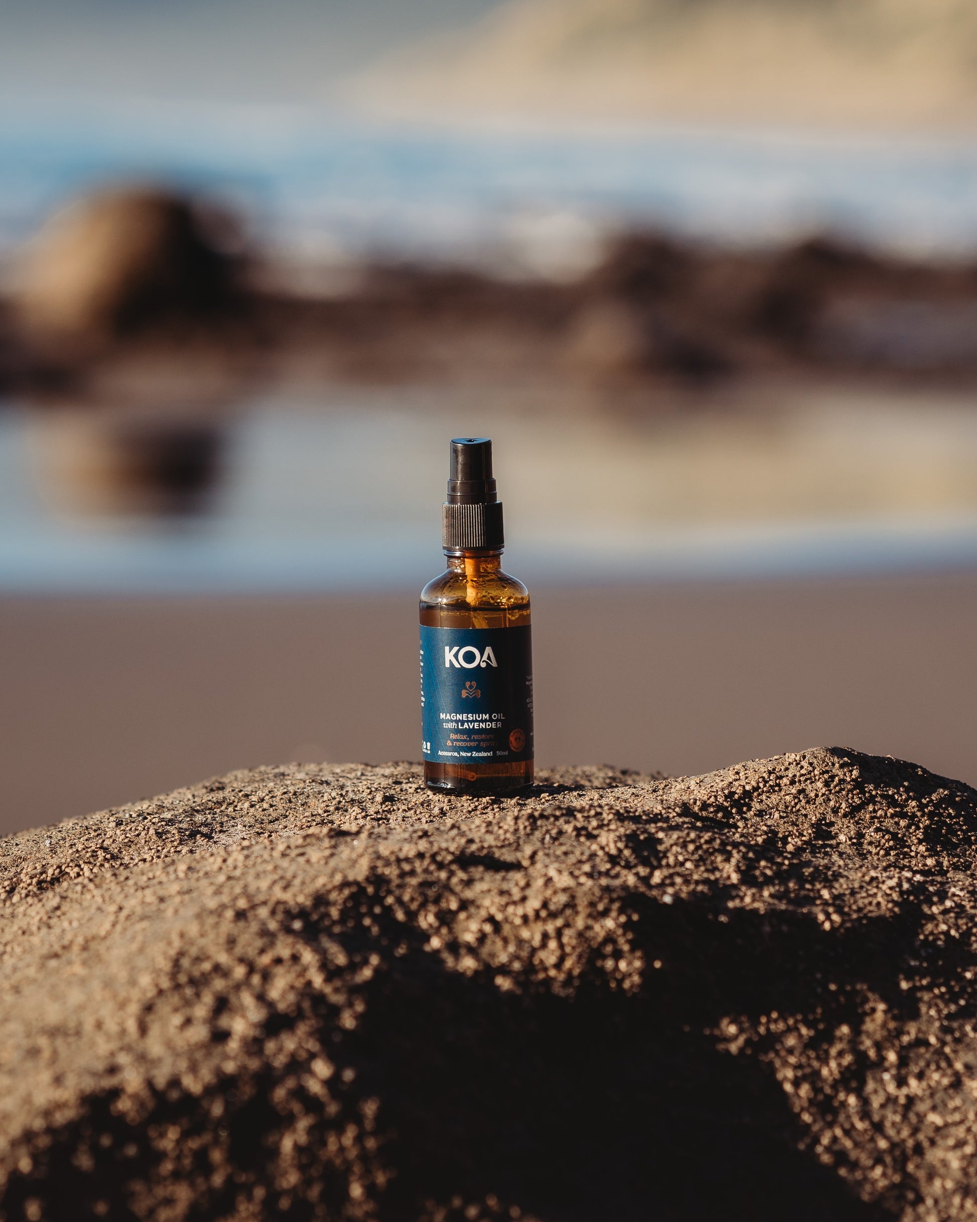 Magnesium Oil with Lavender sitting on a rock with an ocean background.