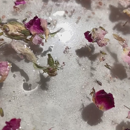 Video of bath water with petals and salt floating gently.